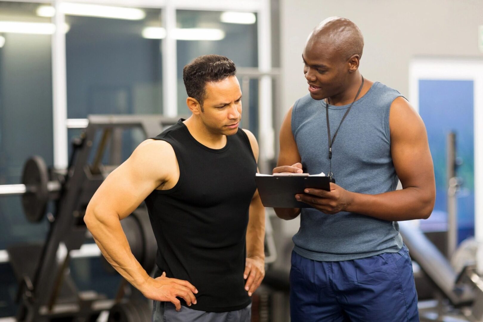 Two men are looking at a tablet in the gym.