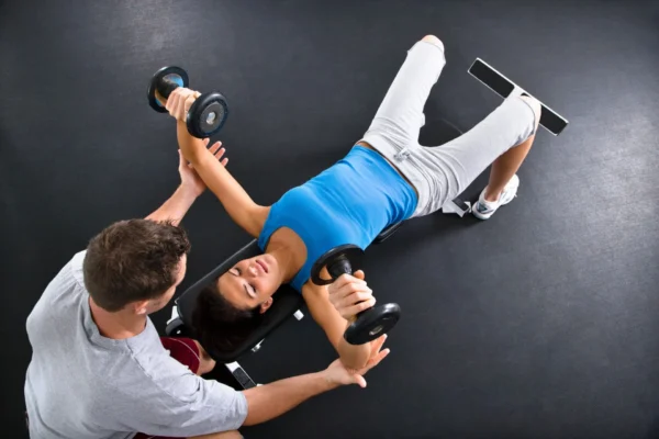 A woman is lying on the ground while holding two dumbbells.