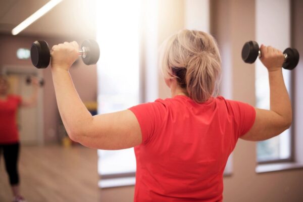 A woman is holding onto two dumbbells in her arms.